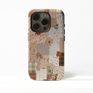 May include: A phone case with a patchwork design. The case features a collage of floral, plaid, and patterned squares in shades of brown, beige, and cream. The camera lenses are visible at the top.