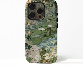 May include: A phone case featuring a whimsical illustration of a frog on a lily pad in a pond. The design includes white water lilies, green lily pads, and the text "healing happens in layers."