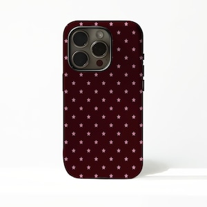 May include: A burgundy phone case with a repeating pattern of small pink stars. The case has a rounded rectangular shape with a camera cutout and black side buttons. The case is designed to fit a smartphone.