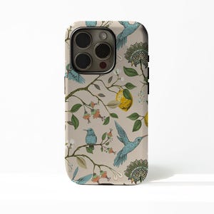 May include: A phone case with a beige background featuring a botanical design. The design includes blue hummingbirds, yellow lemons, and floral elements. The case has a glossy finish and a camera cutout.