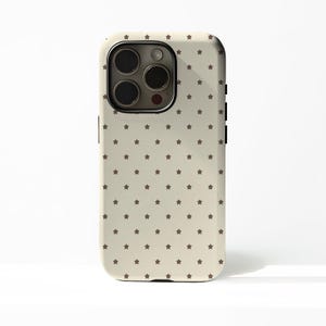 May include: A beige phone case with a repeating pattern of small, dark brown stars. The case has a camera cutout and black side buttons. The phone case is designed to fit a smartphone.