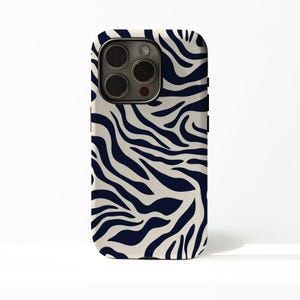 Könnte beinhalten: Smartphone-Hülle mit cremefarbenem Hintergrund und navyblauem Zebrastreifenmuster. Die Hülle hat eine abgerundete rechteckige Form mit Kameraausschnitt und schwarzen Seitentasten.