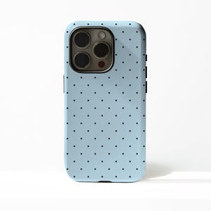 May include: A light blue phone case with a repeating pattern of small black dots. The case has a camera cutout and button details. The phone case is designed to fit a smartphone.