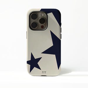 以下が含まれることがあります： クリーム色の背景にネイビーブルーの星柄がプリントされたスマートフォンケース。光沢のある仕上がりで、カメラ用の切り抜きがあります。「777」の文字がケースの下部に印刷されています。