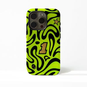 以下が含まれることがあります： 黒い渦巻き模様のネオングリーンの携帯電話ケース。ケースには金の数字1、金の星、小さなスマイリーフェイスが付いています。スマートフォン用です。