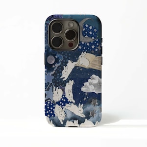 May include: A phone case with a fantasy design. It features white rabbits, stars, clouds, and a crescent moon on a dark blue background. The case has a glossy finish and a camera cutout.