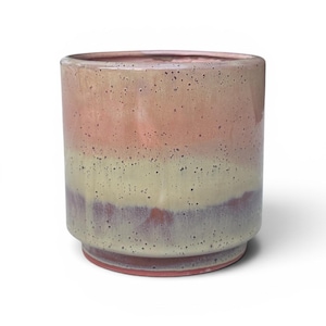 May include: A cylindrical ceramic planter featuring a multi-colored glaze with horizontal bands of muted pink, pale yellow, and deep plum. The surface has a glossy finish with scattered dark speckles throughout, and the base has a stepped design.