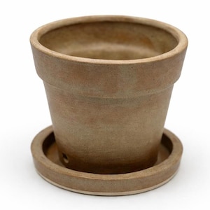 May include: A brown ceramic flower pot with a matching saucer. The pot has a classic shape with a wide rim and a slightly tapered body. The saucer is round and has a raised edge. The pot and saucer are made of a speckled, earthy-toned ceramic.