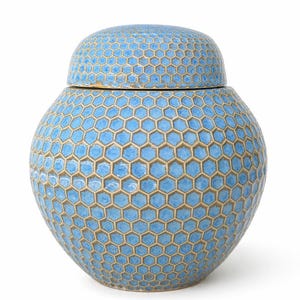May include: A blue ceramic jar with a lid. The jar and lid are covered in a honeycomb pattern with a light brown outline. The jar has a rounded shape and is suitable for home decor.