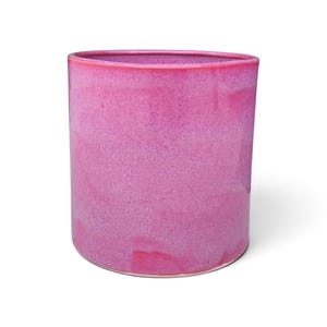 May include: A cylindrical ceramic planter featuring a vibrant, mottled magenta and hot pink glaze. The vessel has a smooth, straight-sided profile with a consistent rim thickness, showcasing a rich, saturated color palette throughout the exterior surface.