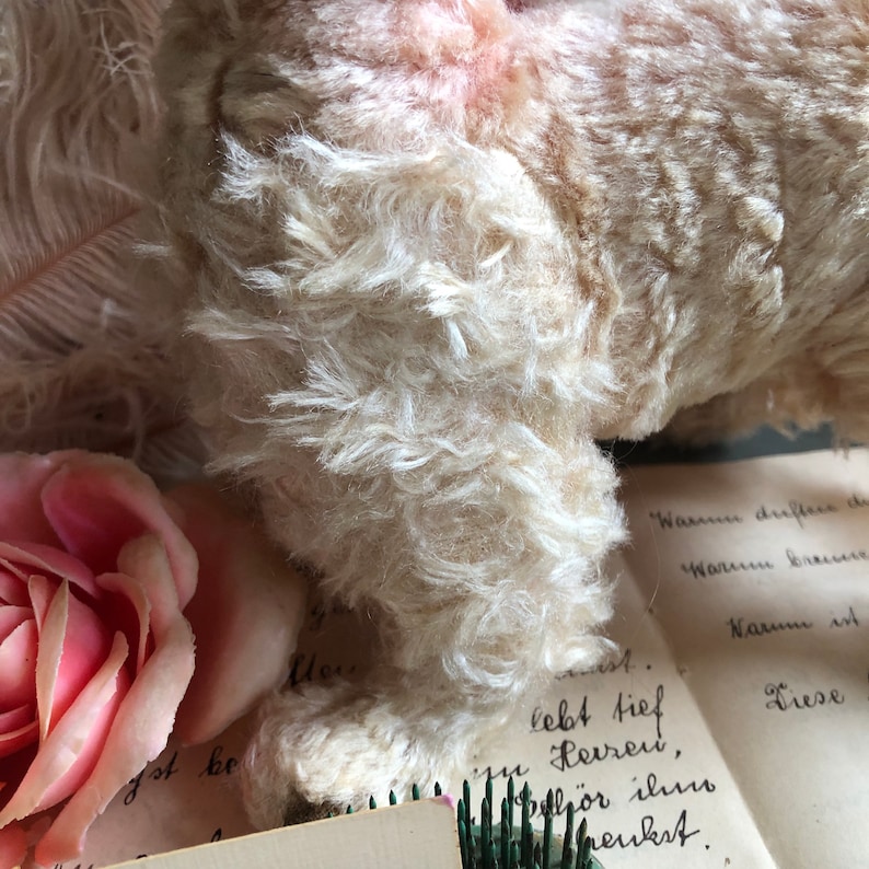 May include: A vintage white plush toy with a soft, fluffy texture. The toy is lying on a piece of paper with handwritten text that reads "Warun driftere de, Warum breur, Narum ist, Liese, lebt tief Herren, h&ouml;r ilmo meukst."
