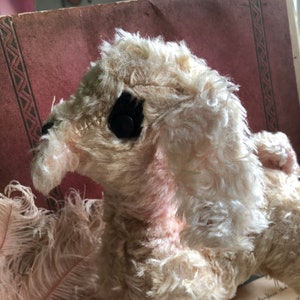 May include: A vintage white plush toy dog with black button eyes. The dog has a fluffy, curly coat and is in a sitting position.