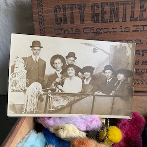 May include: A black and white photo of a group of people in a vehicle. The vehicle has a sign that reads 