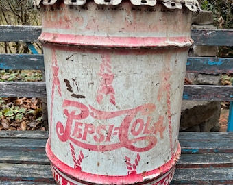 May include: Vintage Pepsi-Cola metal barrel with a distressed white and red finish. The barrel features the Pepsi-Cola logo in red and the text "WITH A DIME 5¢ BIGGER". The barrel is weathered, showing signs of age and use.