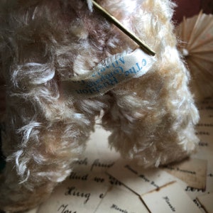 May include: Close-up of a white stuffed animal with a blue and white label that reads "The Original Steiff  Germany".