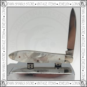 May include: A folding pocket knife with a single upright stainless steel blade and a handle featuring a pearlescent white finish. The blade is stamped with the text CASE XX, and the handle bolster also displays the text CASE XX in a small font.