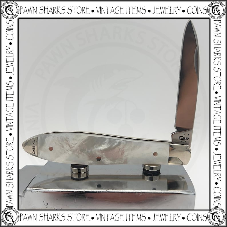 May include: A folding pocket knife with a single upright stainless steel blade and a handle featuring a pearlescent white finish. The blade is stamped with the text CASE XX, and the handle bolster also displays the text CASE XX in a small font.