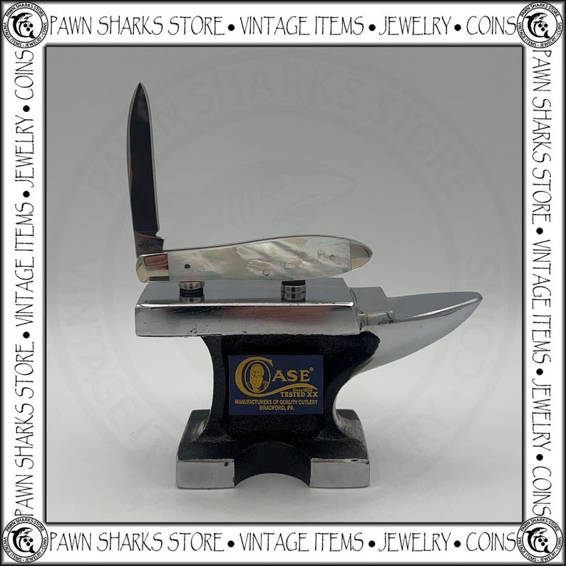 May include: A folding pocket knife with a pearlescent handle and a single upright blade resting on a small, polished metal anvil. The anvil features a blue rectangular label with the text Case, Tested XX, Manufacturers of Quality Cutlery, Bradford, PA.