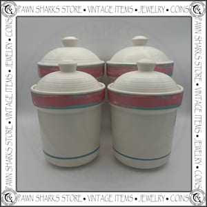 May include: A white ceramic mug with a black handle and the text "But First, Coffee" in a bold, black font. The mug is set against a blurred background, suggesting a cozy setting.