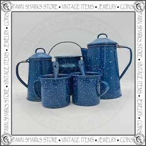 May include: A white ceramic mug with a black handle and the text "But First, Coffee" in a bold, black font. The mug is set against a blurred background, suggesting a cozy setting.