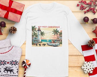 Könnte beinhalten: Weißes Langarmshirt mit einem Key West Christmas-Design. Die Grafik zeigt einen Leuchtturm, Palmen, ein klassisches Auto und den Text "Key West Christmas". Festliche Urlaubsbekleidung.