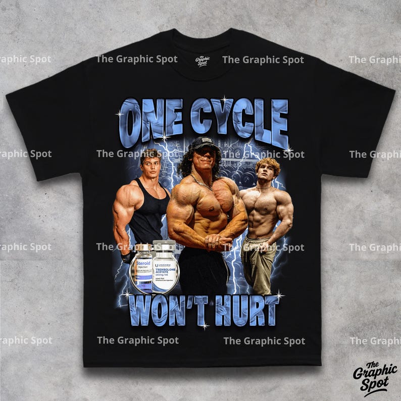 Flat lay of black t-shirt showing full graphic design reading One Cycle Wont Hurt with three illustrated bodybuilders and a supplement bottle, The Graphic Spot brand tee