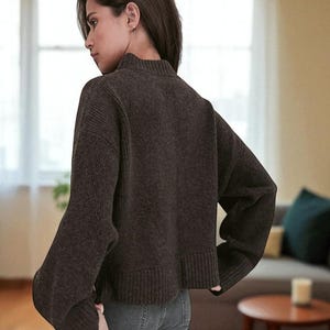 Peut inclure: Un pull &agrave; col montant marron fonc&eacute; avec des manches longues. Le pull a un ourlet et des poignets c&ocirc;tel&eacute;s. Le mod&egrave;le porte le pull avec un jean bleu. Le pull est un v&ecirc;tement d&eacute;contract&eacute; de tous les jours.