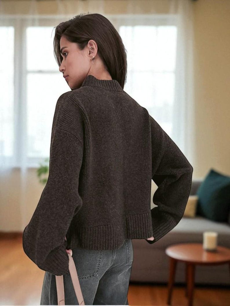 Peut inclure: Un pull &agrave; col montant marron fonc&eacute; avec des manches longues. Le pull a un ourlet et des poignets c&ocirc;tel&eacute;s. Le mod&egrave;le porte le pull avec un jean bleu. Le pull est un v&ecirc;tement d&eacute;contract&eacute; de tous les jours.