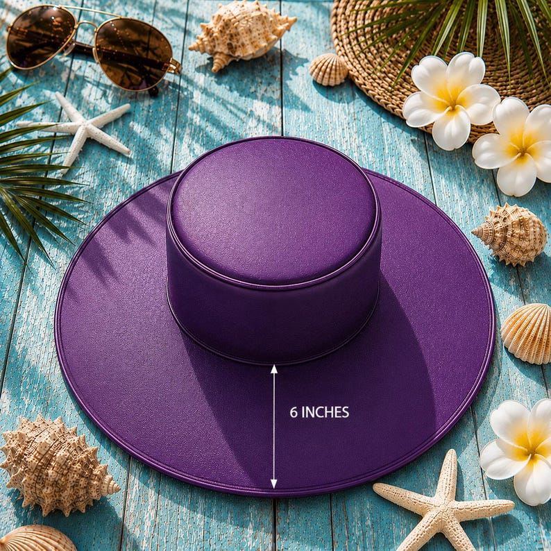 Puede incluir: Un sombrero morado vibrante con un ala de 15 cm, rodeado de conchas marinas, estrellas de mar y gafas de sol sobre una superficie de madera azul desgastada. El sombrero tiene una corona redonda y un ala ancha y plana.