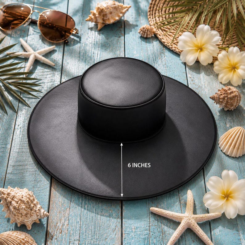 Puede incluir: Un sombrero negro para el sol con un ala de 15 cm, rodeado de conchas marinas, estrellas de mar y gafas de sol. El sombrero tiene una copa redonda y un ala ancha. La imagen est&aacute; sobre una superficie de madera azul claro, evocando un tema de playa.