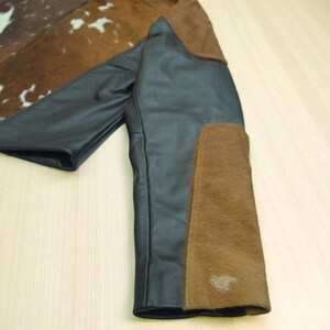 May include: A black leather jacket with brown suede patches on the sleeves and shoulders. The jacket has a unique design with a cowhide pattern on the upper back and collar.