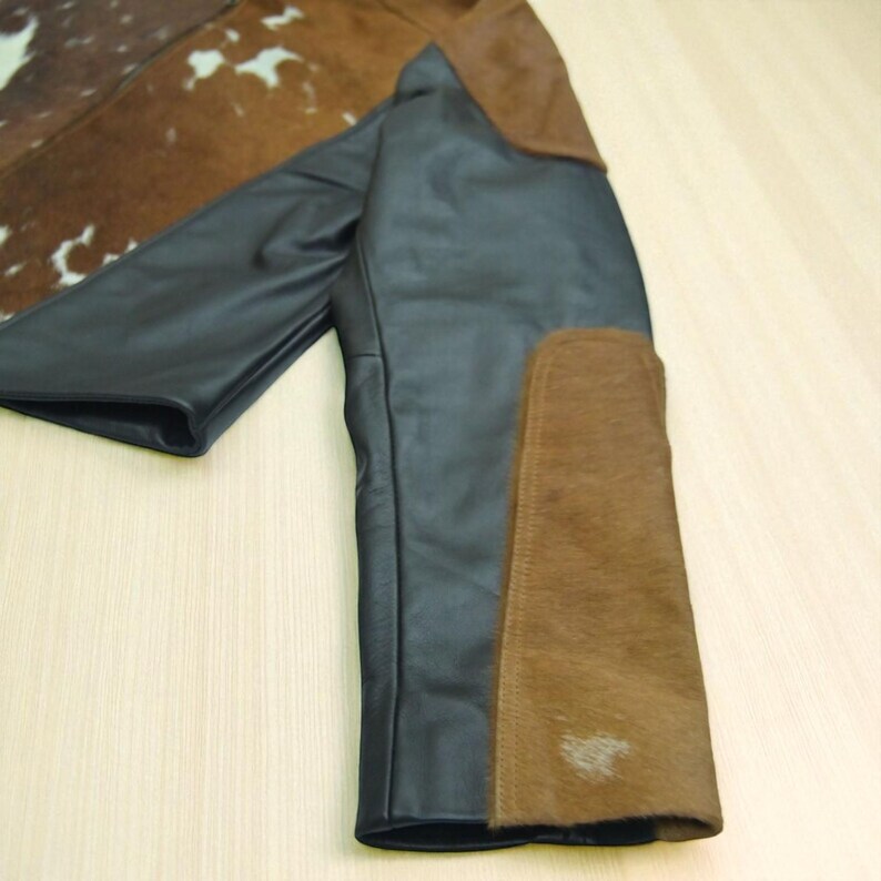 May include: A black leather jacket with brown suede patches on the sleeves and shoulders. The jacket has a unique design with a cowhide pattern on the upper back and collar.