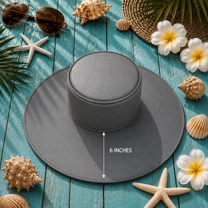 Puede incluir: Sombrero gris con ala de 15 cm, exhibido con conchas marinas, gafas de sol y flores tropicales. El sombrero tiene un dise&ntilde;o sencillo, ideal para la protecci&oacute;n solar.