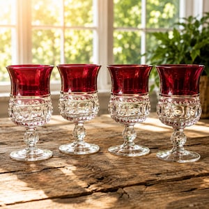 Puede incluir: Un juego de cuatro copas con cuencos de cristal rojo intenso y bases de cristal transparente texturizado. Cada copa tiene un borde rojo ancho y liso que se transforma en un patrón facetado detallado en la parte inferior y un pie redondo y firme.