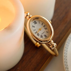 Zierliche Gold Manschetten Uhr, ovale römische Ziffern Armbanduhr, gedrehtes Draht Band, elegantes Vintage Geschenk für ihren Jahrestag Valentine