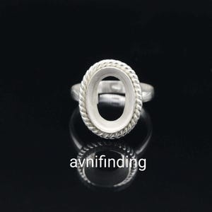 May include: A silver ring with an oval setting, featuring a twisted rope design around the bezel. The ring is set against a black background, with the brand name "avnifinding" visible at the bottom.