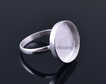 Könnte beinhalten: Ein silberner Ring mit einer ovalen Lünettenfassung. Der Ring besteht aus glänzendem Metall und hat eine glatte, polierte Oberfläche. Die Lünette ist so konzipiert, dass sie einen Stein oder ein anderes dekoratives Element aufnehmen kann. Der Ring wird vor einem dunklen Hintergrund gezeigt.