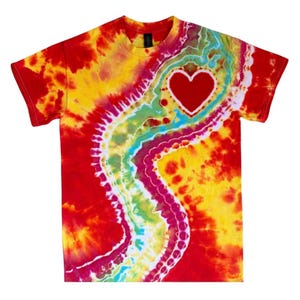 May include: A tie-dye t-shirt with a red heart shape in the center. The shirt features a vibrant mix of colors, including red, yellow, green, and blue, creating a psychedelic pattern. The shirt has short sleeves and a crew neck.