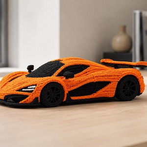 May include: A handcrafted crochet toy sports car in bright orange and black yarn. The vehicle features a detailed aerodynamic body, a rear spoiler, black wheels, and a textured surface created with intricate stitching throughout the design.