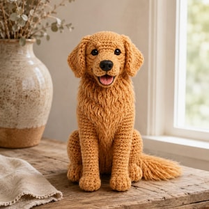 May include: A golden-colored crocheted dog figurine with floppy ears, a black nose, and an open mouth showing a pink tongue. The stuffed animal features textured yarn detailing on the chest and tail, mimicking the appearance of a golden retriever.