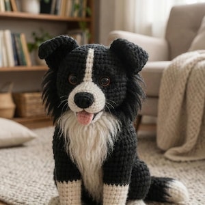 Op de afbeelding: Een handgemaakte gehaakte hond in een zittende positie, met zwart en wit garen. De hond heeft een witte streep op zijn gezicht, een witte borst en een roze tong. De hond zit op een grijs tapijt.