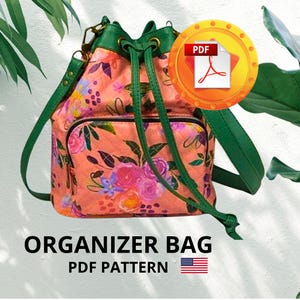 Peut inclure: Sac organisateur à imprimé floral avec des sangles et une fermeture à cordon verts. Le sac présente un fond pêche avec des fleurs roses et violettes. Le texte "ORGANIZER BAG PDF PATTERN" est affiché en dessous, avec une icône PDF.