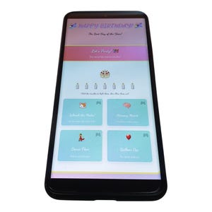 Puede incluir: Un teléfono inteligente negro muestra una interfaz de aplicación con temática de cumpleaños. La pantalla presenta el texto "HAPPY BIRTHDAY!" y "The Best Day of the Year!" con opciones de juego interactivas. La aplicación tiene un esquema de color claro con ilustraciones.