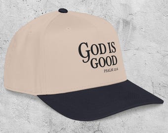 Może przedstawiać: Beżowa czapka z daszkiem z granatowym daszkiem. Na czapce widnieje napis "GOD IS GOOD" czarną czcionką, z napisem "PSALM 23:6" poniżej. Na górze czapki znajduje się czarny guzik.