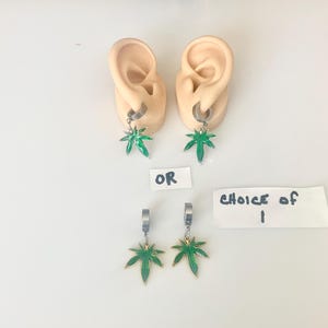 May include: Earrings with green marijuana leaf pendants. The earrings are displayed on ear models, with the text "OR" and "CHOICE OF 1" visible.