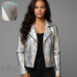 May include: Silver holographic biker jacket with black zips and a notched collar. The jacket has a small pocket on the front and a shiny, iridescent finish. The jacket is shown on a person wearing a black top and black jeans.