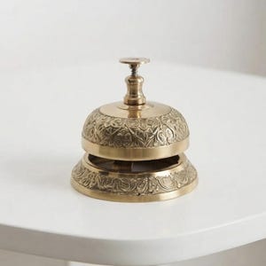 Handmade brass call bell with antique engraved design and polished gold finish, perfect vintage reception desk bell for hotel, restaurant counter or office table decor.