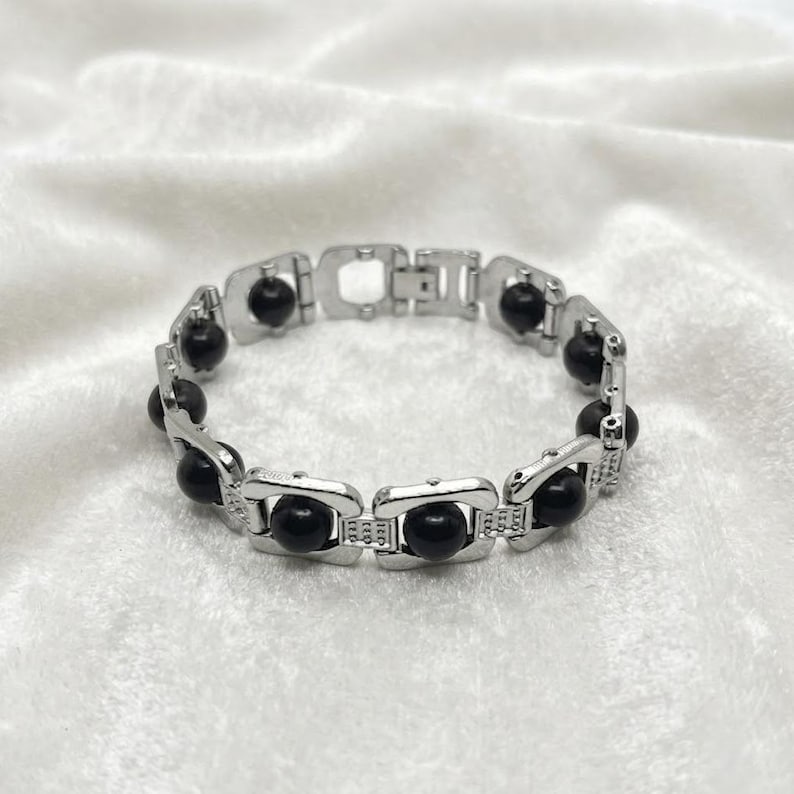 Karungali bracelet featuring natural black ebony wood beads set in linked metal frame, designed for spiritual protection and root chakra grounding energy.