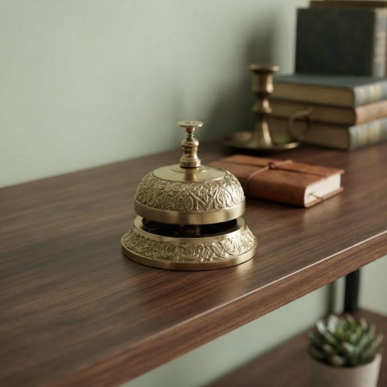 Handmade antique brass desk bell crafted with detailed engraving and durable mechanism, perfect hotel lobby decor piece.