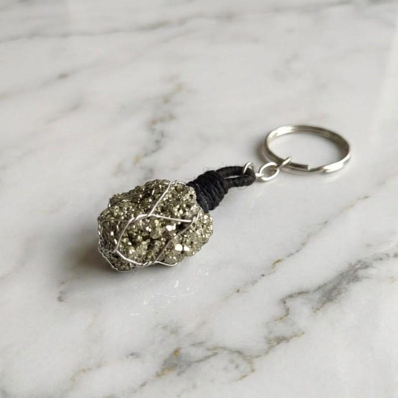 Raw pyrite gemstone keychain shown on wooden surface
